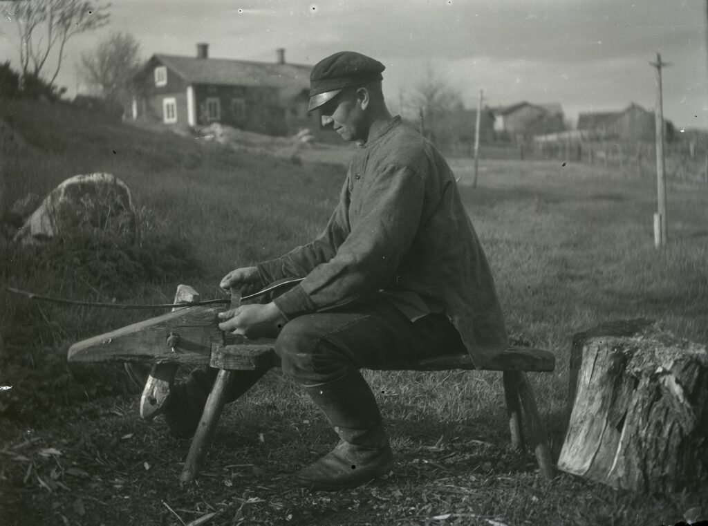 En man sitter på en bänk och täljer.