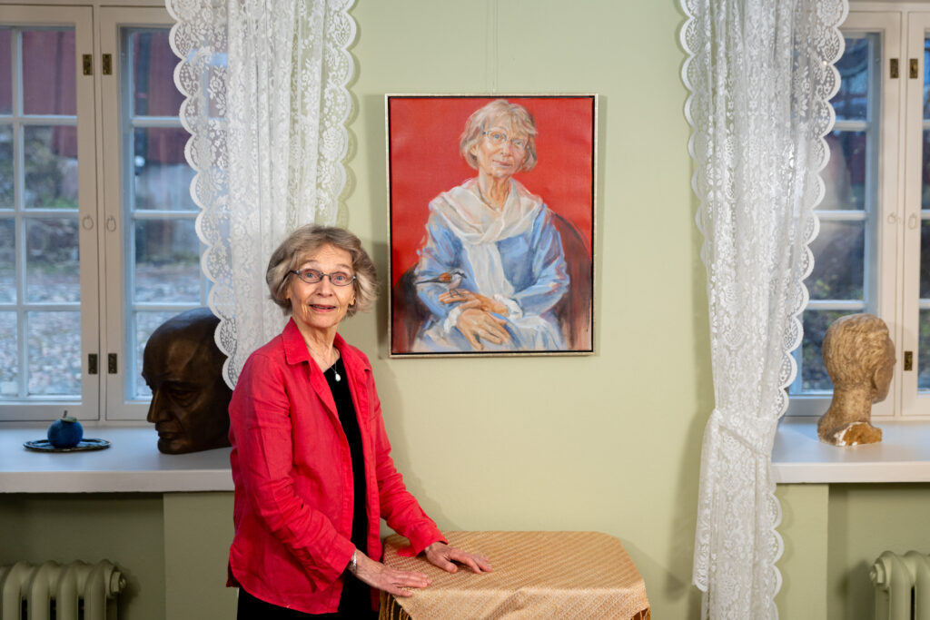 En kvinna står framför ett självporträtt