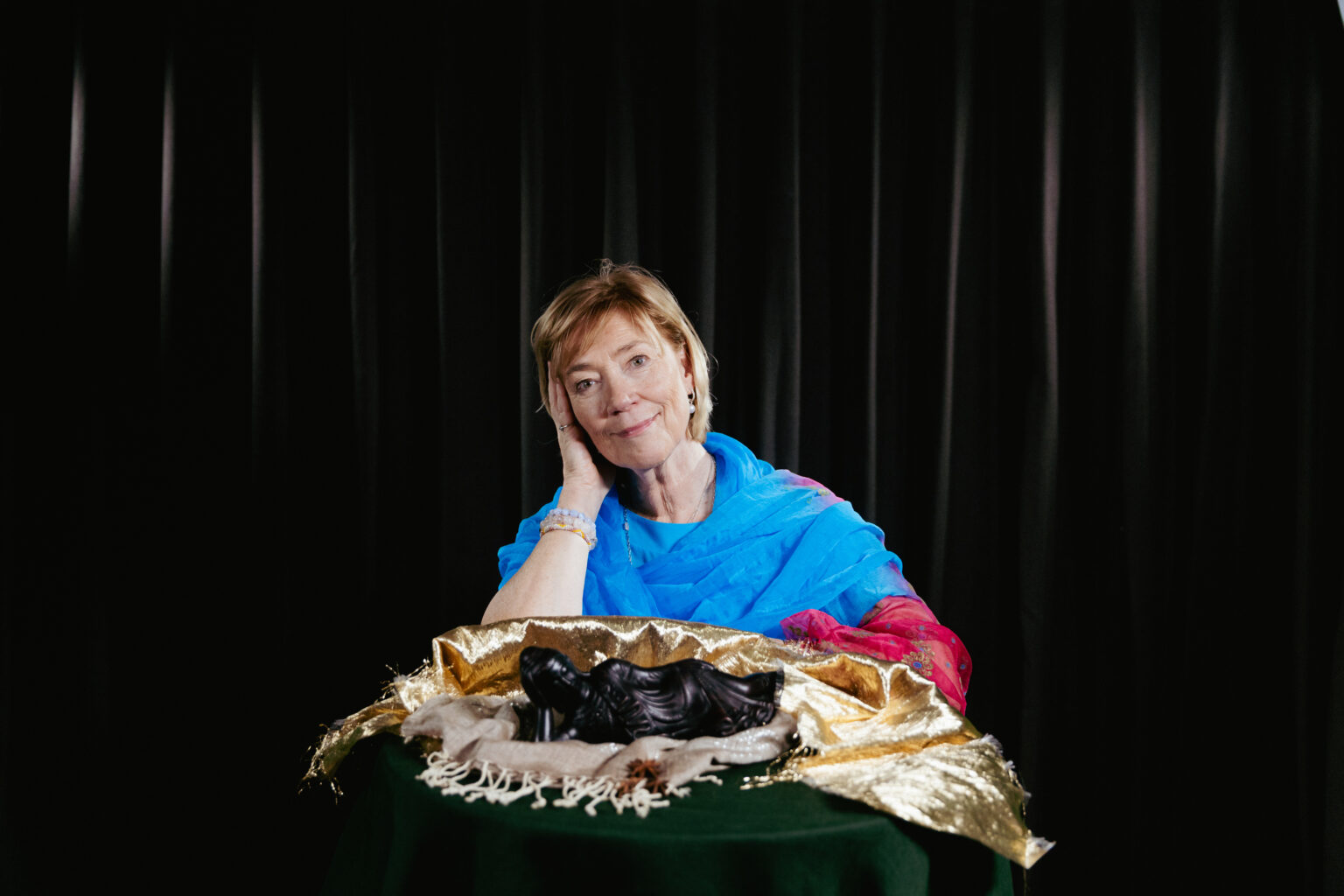 kvinna bakom ett bord med en staty och tygstycken