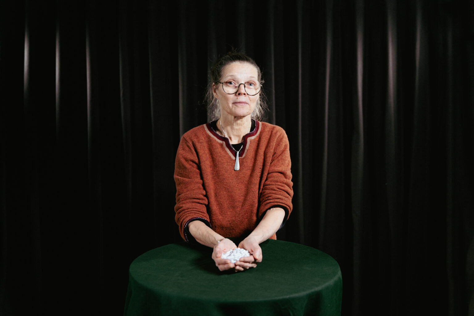 Kvinna vid ett bord håller medicin i händerna