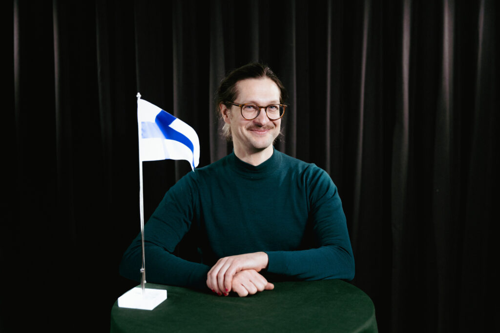 man bakom ett bord med ett standard med finlands flagga