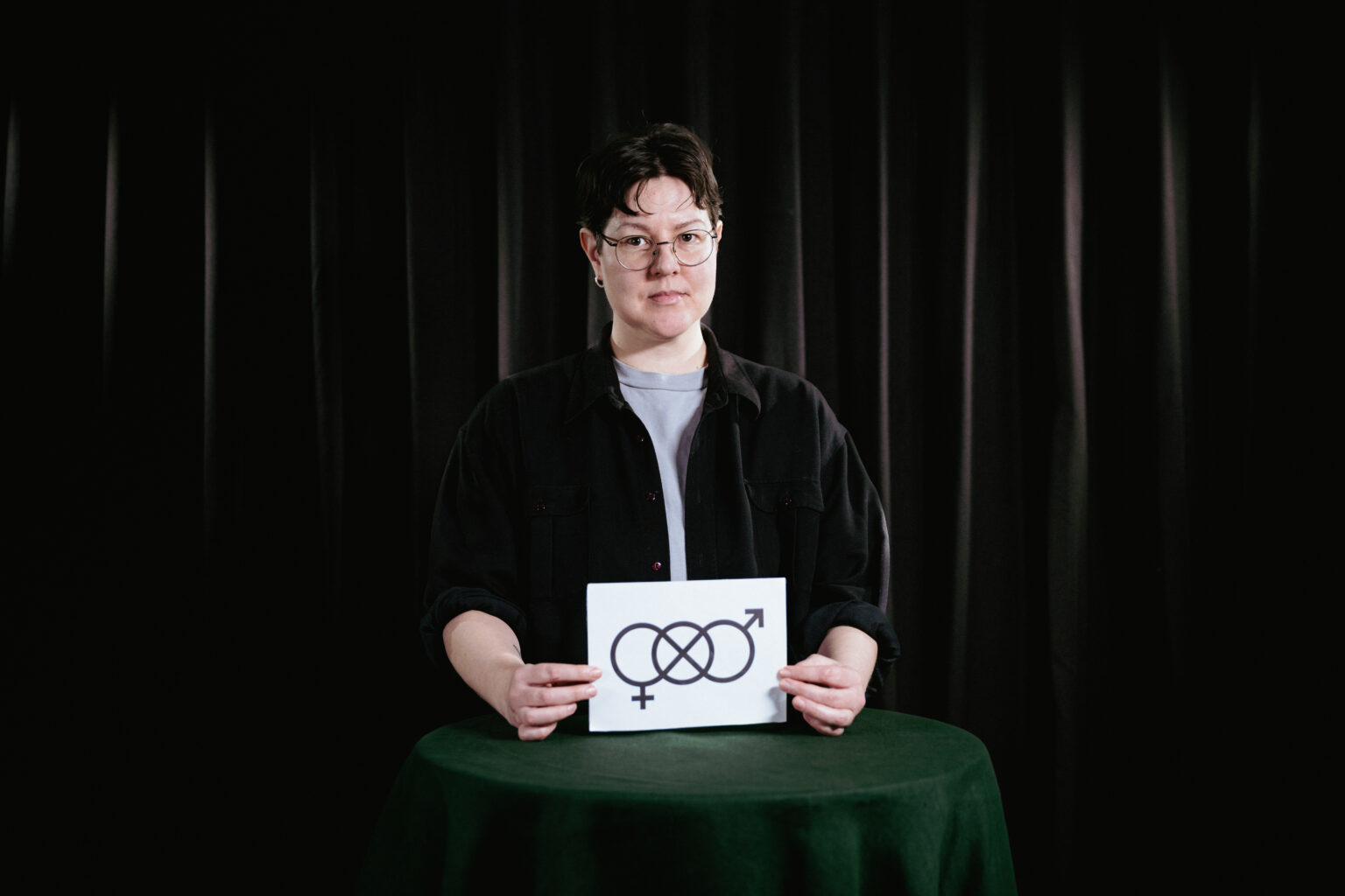 person med skylt med genderneutral symbol i handen